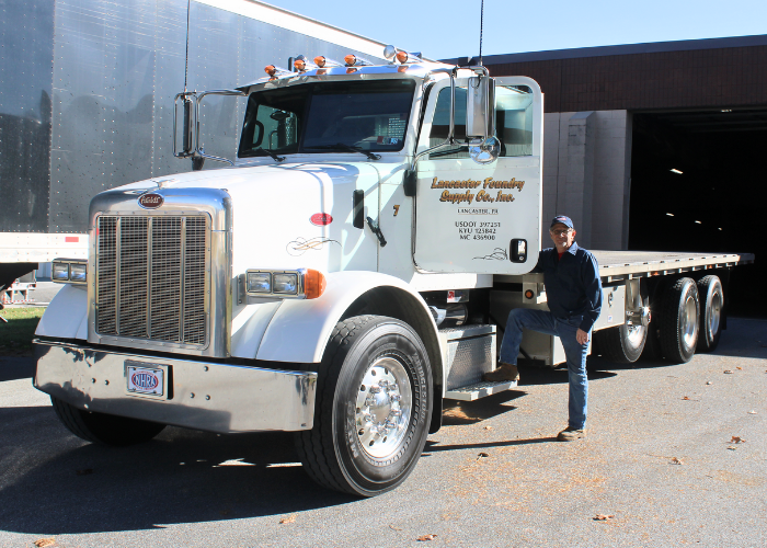 Man, employee posing next to a Lancaster Foundry Supply Company flatbed truck