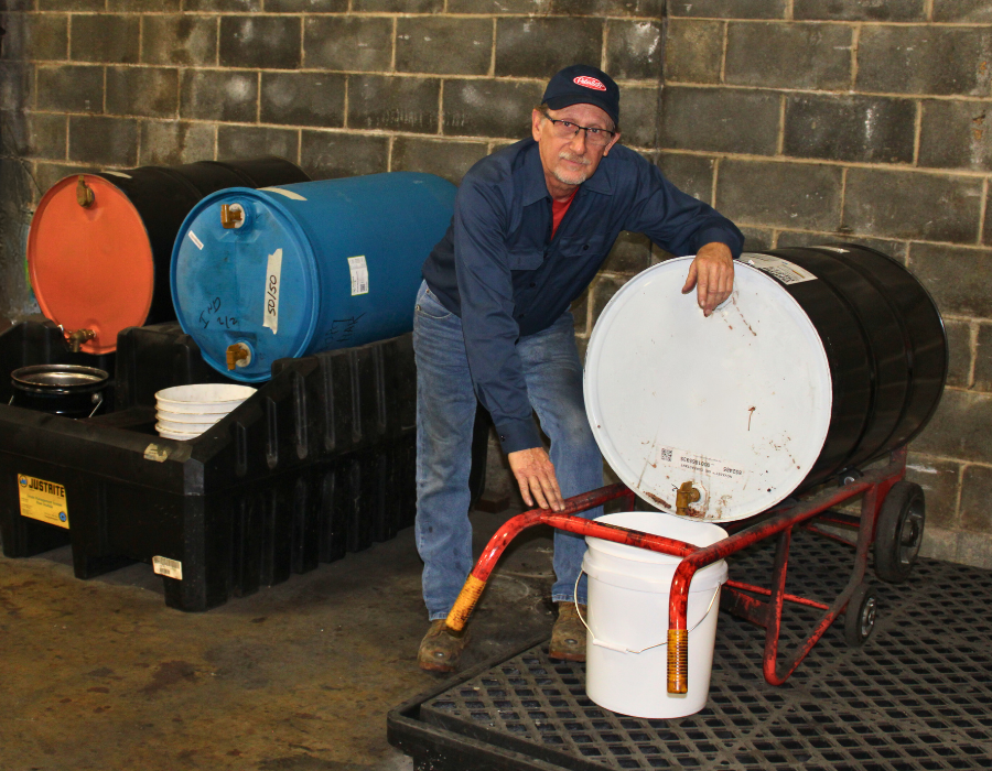 Male employee posing next to a drum of liquid