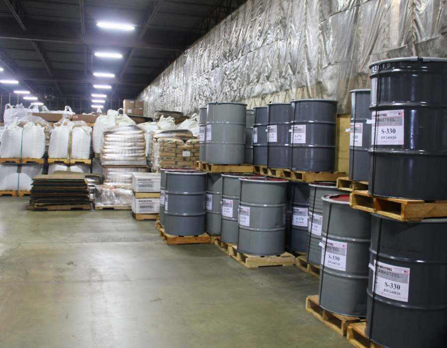 Pallets holding drums of Ervin Industries AMASTEEL abrasive and other foundry supplies inside of a warehouse