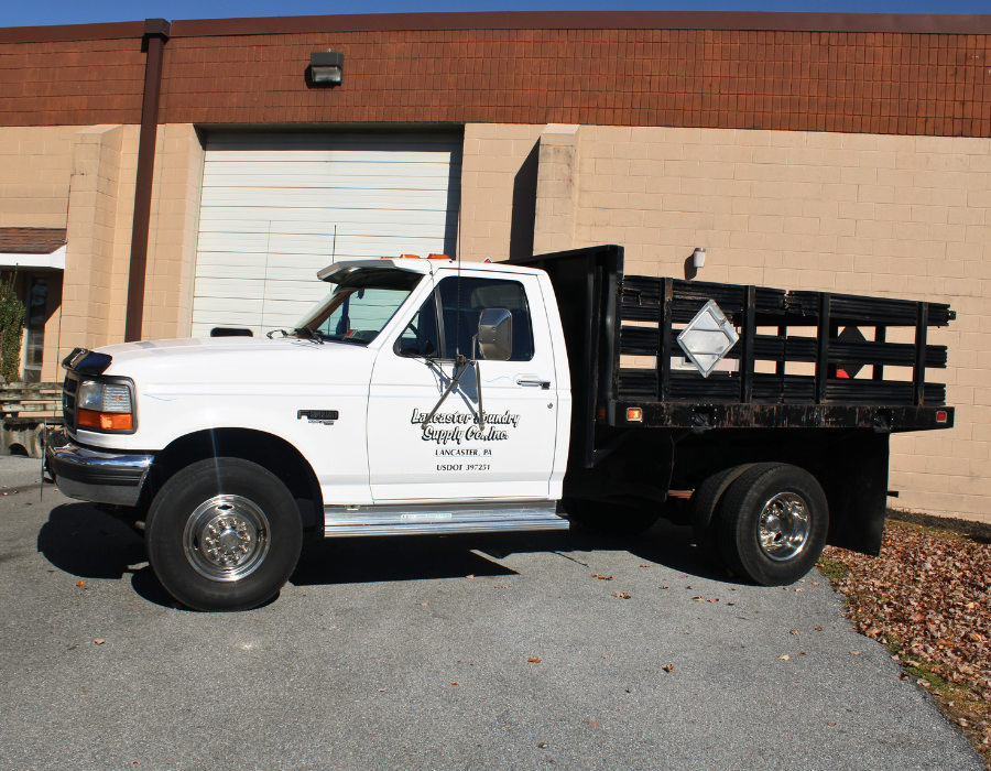 A white and black Lancaster Foundry Supply Company truck parked outside building